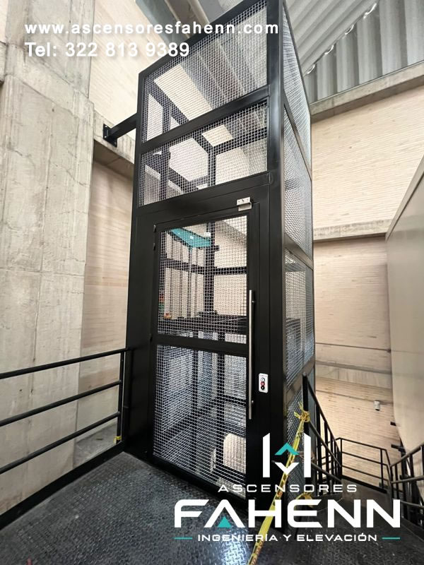 Torre metálica para ascensor de carga con malla de alta seguridad, puerta frontal, tirador y plataforma.