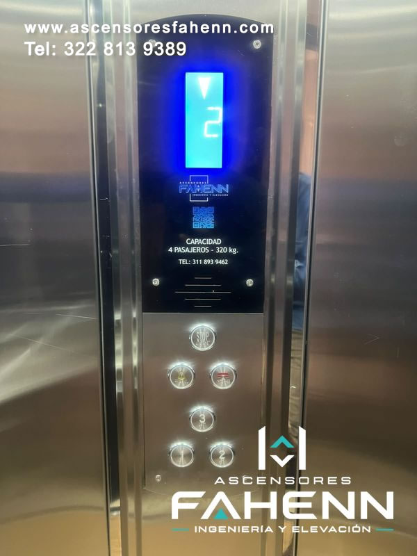 Panel de control para ascensor con pantalla de piso, indicador de dirección y botones LED iluminados que facilitan el manejo dentro de la cabina.