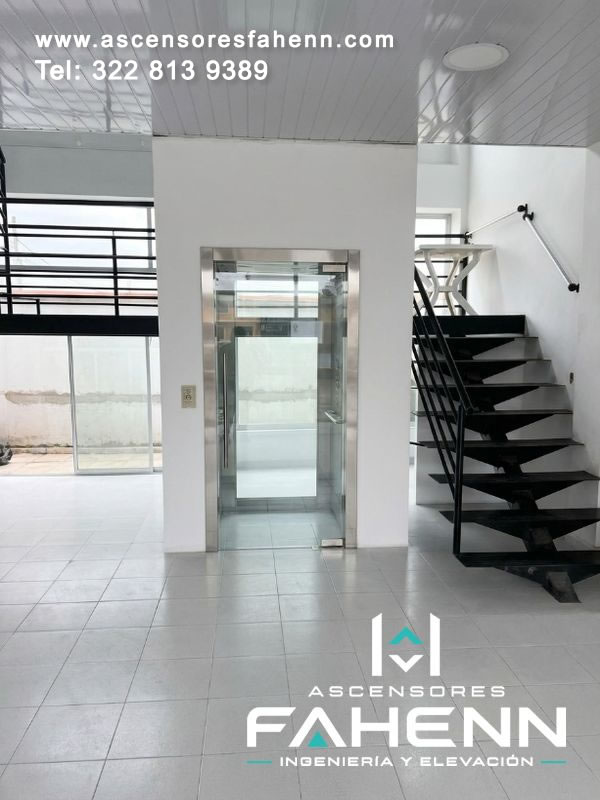 Ascensor panorámico para edificio con cabina de vidrio, estructura compacta y puerta transparente que conserva la conexión visual con el espacio interior.