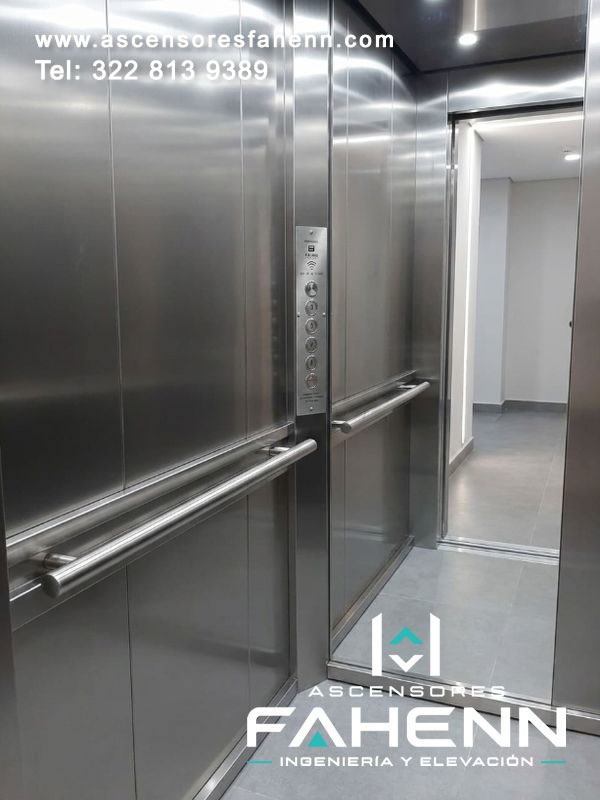 Cabina de acero inoxidable con acceso amplio, barandas en ambos laterales, controles alineados y piso continuo para movilidad vertical accesible.