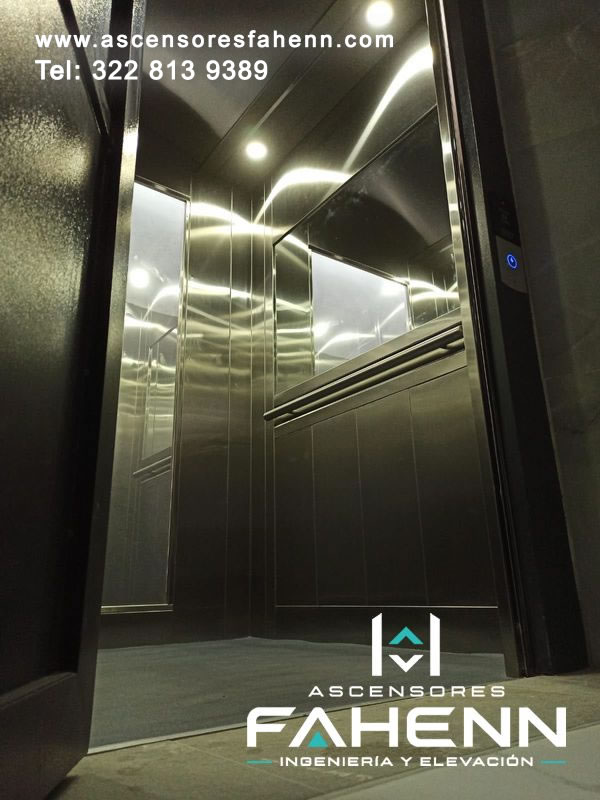 Cabina premium de ascensor con grandes espejos, paneles de acero inoxidable, pasamanos horizontal y luces LED reflejadas en superficies brillantes.