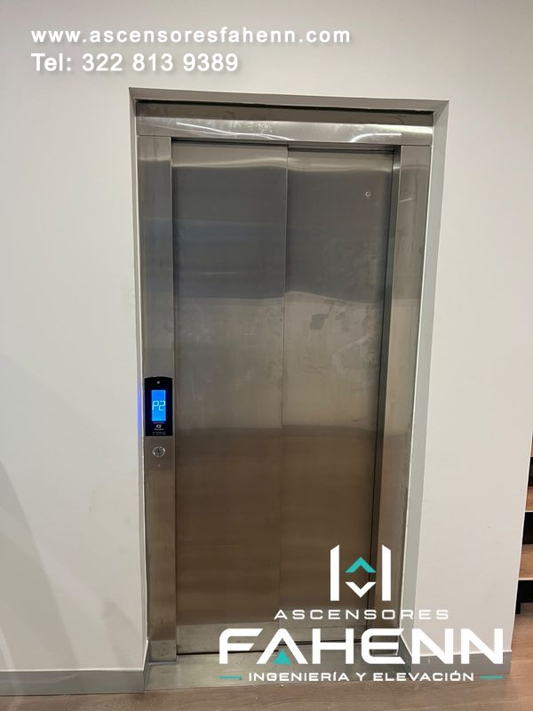 Puertas automáticas de acero para ascensor con superficie reflectiva, marco inoxidable, indicador digital P2 y pulsador exterior.