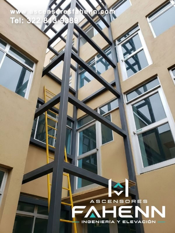 Torre metálica para elevador instalada en el patio de un edificio, con perfiles resistentes y diseño vertical adaptado para conectar niveles con seguridad.