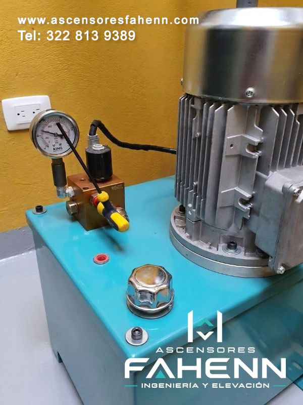 Motor eléctrico y manómetro para sistema hidráulico de ascensor con válvulas y conexiones accesibles para controlar la presión en Bogotá, Colombia.